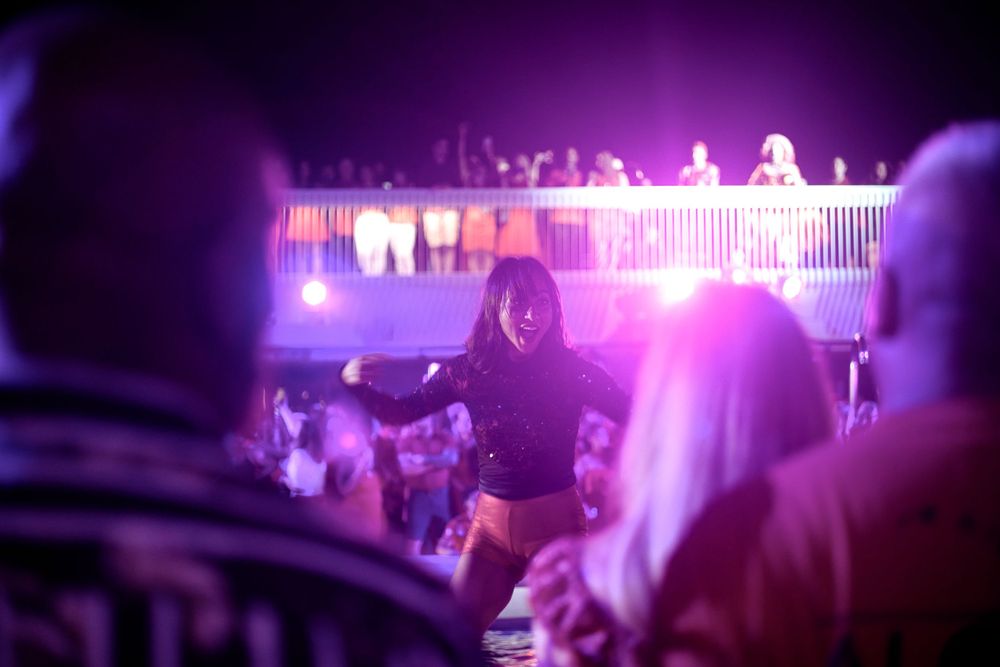 Concert crowd scene with purple stage lighting and silhouettes.