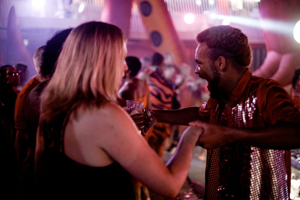 Two people interacting at a nightclub with purple ambient lighting.