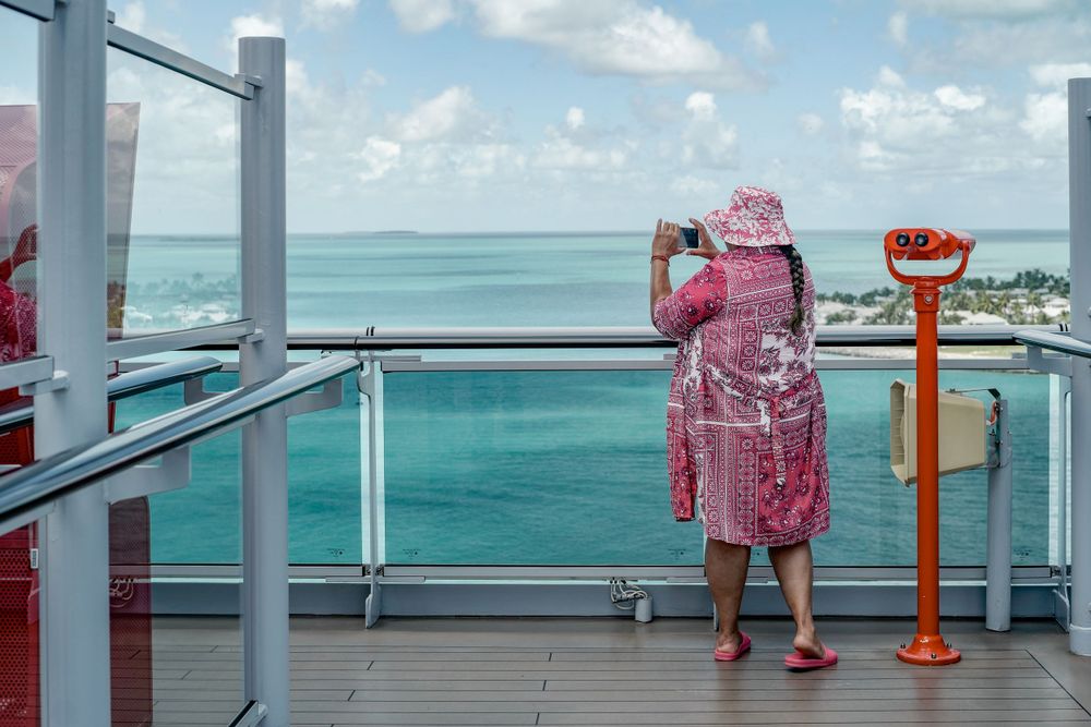 Viewer looking through observation equipment on a cruise ship deck overlooking the ocean.