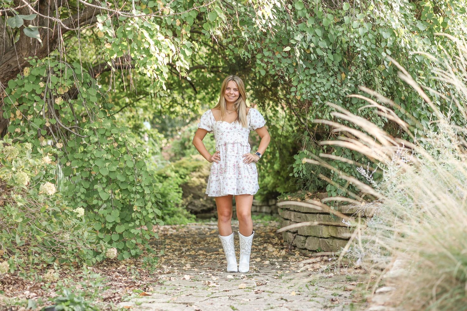 Nature-inspired fashion photo featuring a white dress and boots on a garden path.
