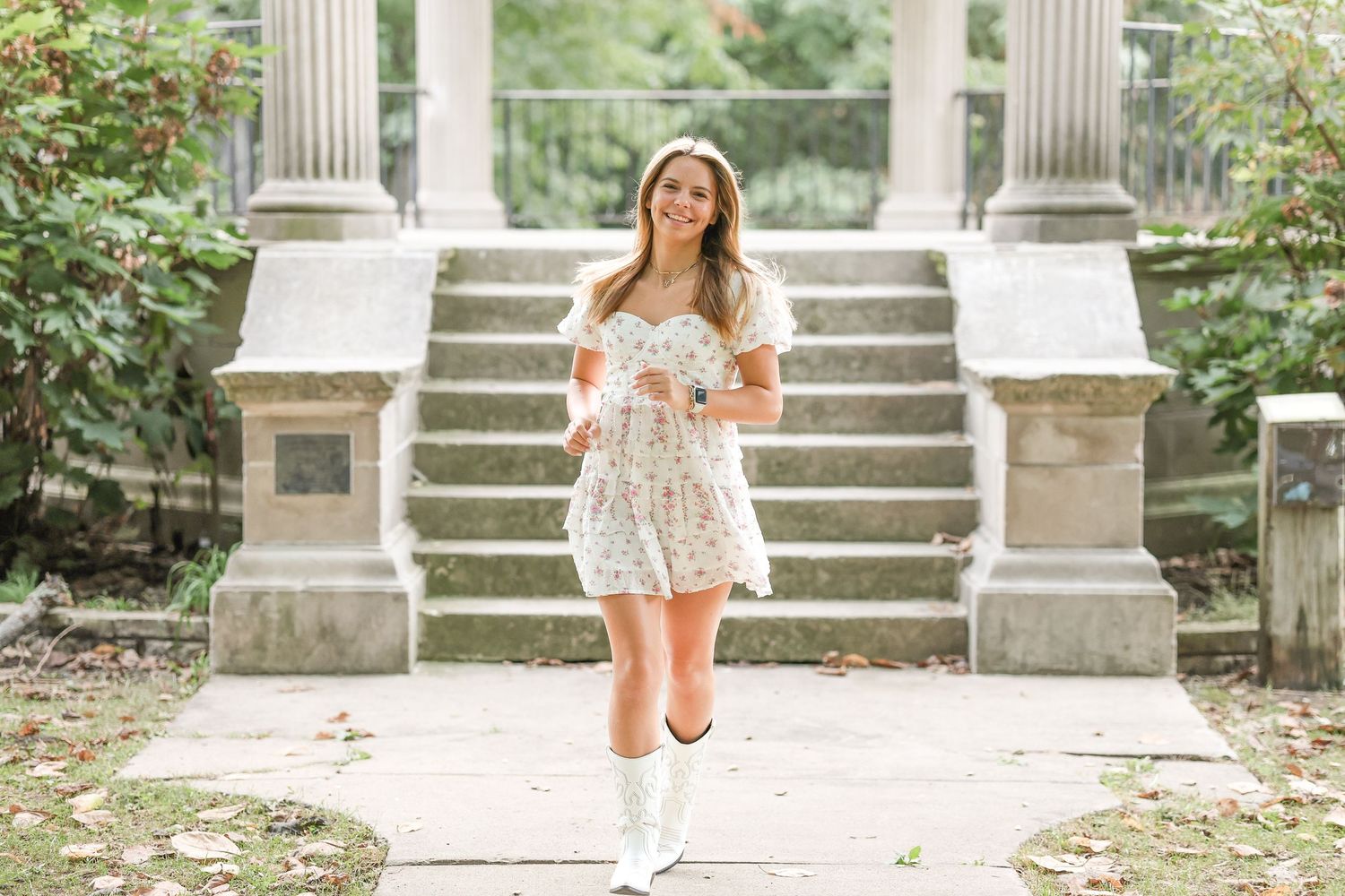 A summery white dress ensemble photographed on classical stone steps in a garden setting.