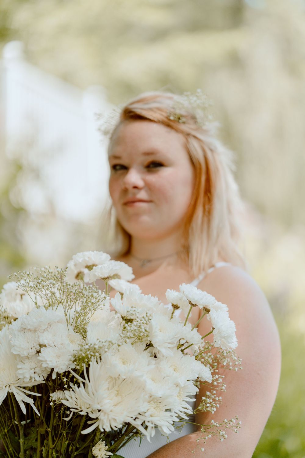 Romantic outdoor portrait featuring white flowers and soft, natural lighting.