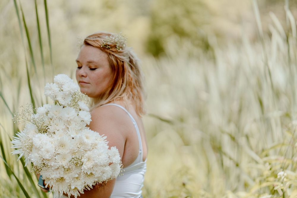 Dreamy profile portrait with white flowers against a soft, sun-lit natural background.