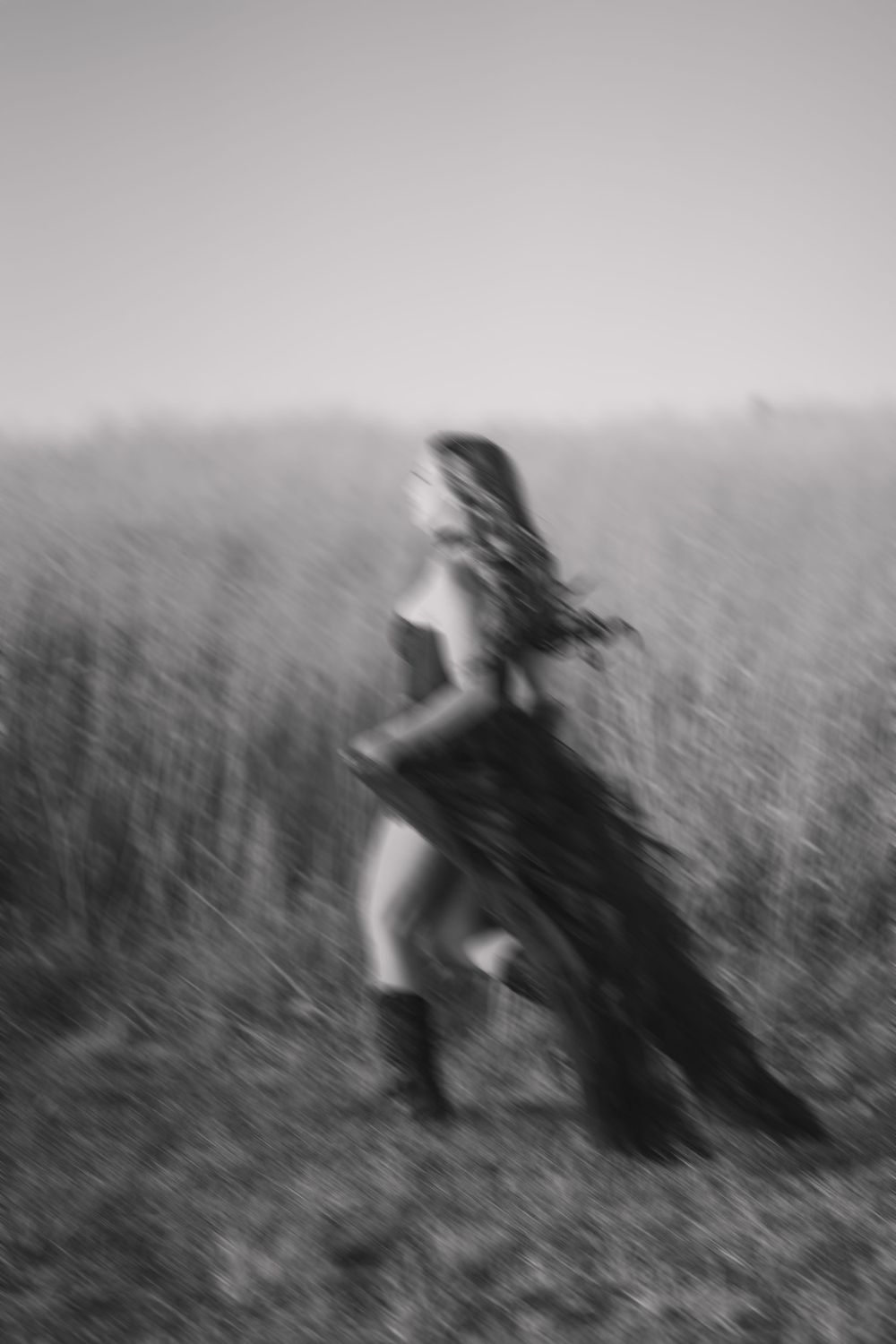 Artistic blurred black and white photo of a figure running through a field.