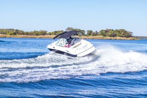 White speedboat jumping over waves in blue ocean waters on a sunny day.