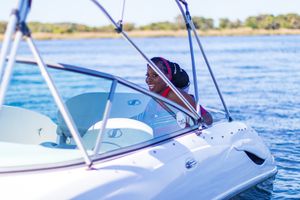 White speedboat with blue canopy sailing on calm waters on a sunny day.