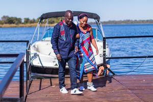 Couple standing together on a dock next to a white boat on a sunny afternoon.