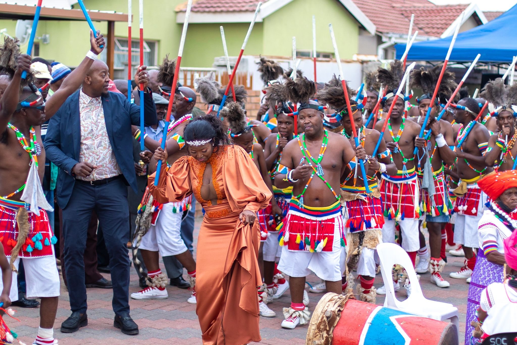 Cultural celebration with people in traditional dress and performers in street parade.