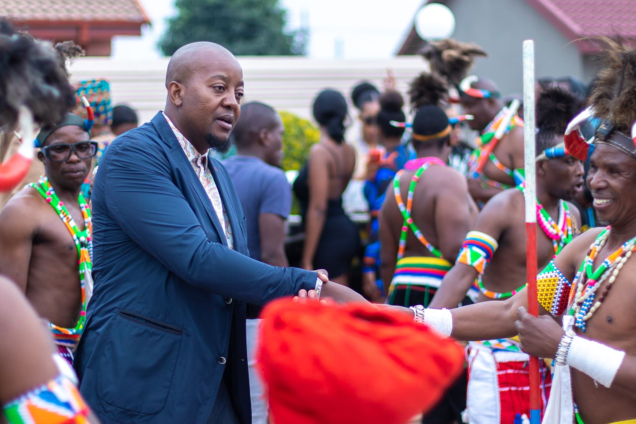 Person in blue suit interacting with guests at a traditional cultural wedding celebration.