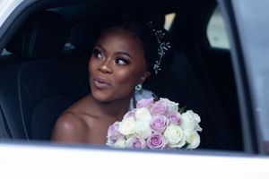 Wedding day moment captured in car with bouquet of pink and white roses.