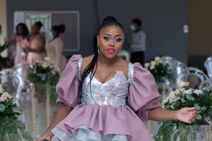 Wedding fashion featuring pink and white ruffled dress with puff sleeves amid floral decorations.