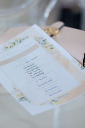 Elegant wedding invitation with delicate floral border design on pink background.
