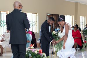 Wedding ceremony taking place in a venue with floral arrangements and seated guests.