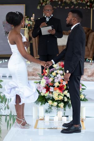 Wedding ceremony featuring elegant floral arrangements and decorative candles on a white platform.