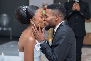 Romantic wedding ceremony moment with floral decorations in the background.