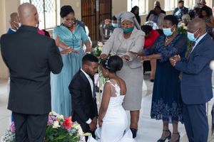 Wedding ceremony scene with guests gathered around in formal attire.