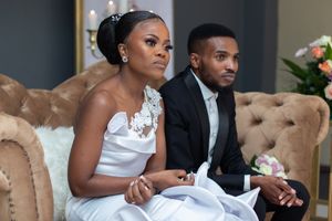 Newlyweds seated on a tufted brown couch during their wedding celebration.