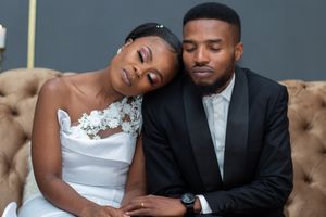 A tender moment between newlyweds as they rest together on a brown tufted couch.