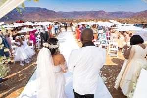 An outdoor wedding ceremony with guests gathered on a mountaintop setting with desert landscape in the background.