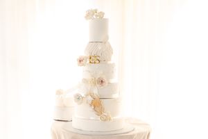 Elegant white wedding cake decorated with delicate blush floral accents.