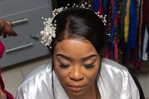 Close-up of bridal preparation with pearl headpiece and satin robe.