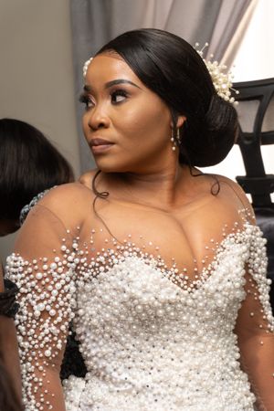 A stunning bridal look featuring a white beaded gown with sheer details and pearl embellishments.