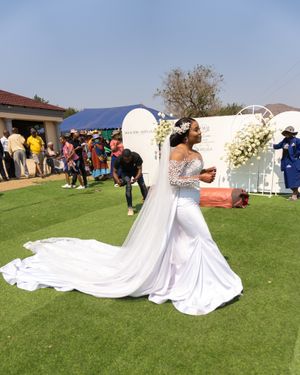 Outdoor wedding ceremony with bride in flowing white gown and long train.