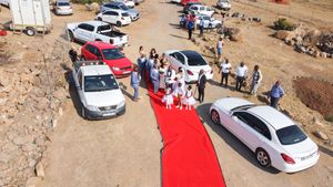 Aerial view of cars lined up along a red carpet pathway at an outdoor desert venue.