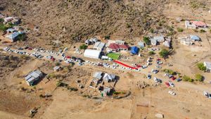 Bird's eye view of rural wedding setup with red pathway winding through desert terrain.