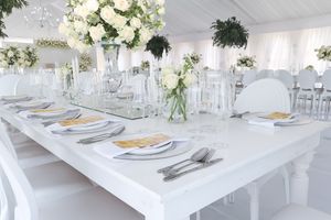 White wedding reception table setting with fresh floral centerpieces and elegant place settings.