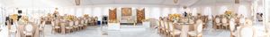 Luxurious wedding reception setup with orange and white floral centerpieces and gold decor.