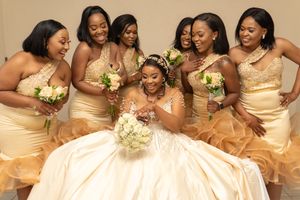 Bridesmaids in gold dresses surround bride in white gown during wedding celebration.