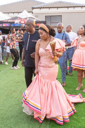 Couple dancing at outdoor celebration in pink mermaid dress and black casual wear.