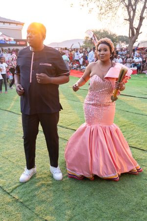 Couple enjoying outdoor festivities in pink formal dress and black casual attire.