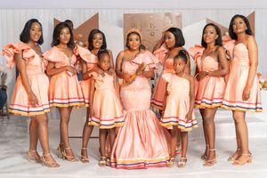 Group of women and children in matching peach-colored dresses posing for a formal photo.