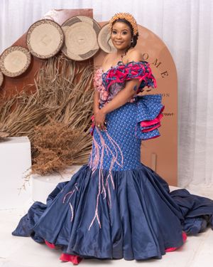 Blue and pink mermaid gown with detailed embellishments against rustic backdrop.
