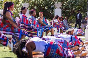 Group wearing colorful traditional African attire performing a cultural celebration outdoors.