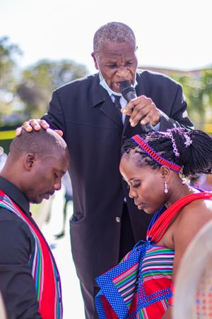 Traditional African wedding ceremony with officiant and couple in cultural attire.