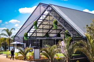 Modern glass and steel wedding venue with palm trees and contemporary architectural design.