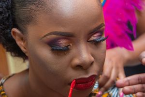 Close up of beautiful eye makeup with purple eyeshadow and fluttering lashes on dark skin.