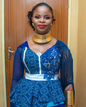 Traditional African dress in blue with gold neckpiece and white trim details.