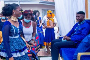 Wedding celebration with guests in traditional African attire and face masks.
