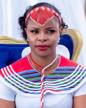 Traditional African bridal wear featuring red beaded headpiece and striped collar design.