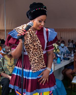 Singer performs in traditional African dress with leopard print and burgundy patterns.