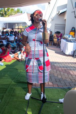 Traditional African dress with red and white stripes during outdoor performance.