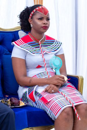 Modern African fashion featuring white dress with red and blue striped patterns.