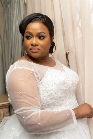 Bride in elegant white wedding dress with sheer sleeves and detailed beadwork.