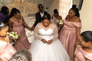 Wedding party gathered around bride in white ball gown with bridesmaids in pink dresses.
