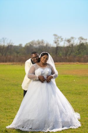 A romantic wedding photo of a couple embracing in a field on their special day.