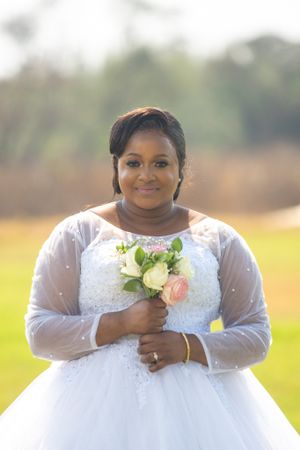 Bride wearing an elegant white gown holds a delicate bouquet of pink and white flowers.